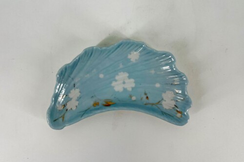 Crescent-shaped blue porcelain plate with white cherry blossoms and gold accents on a pale blue glaze.