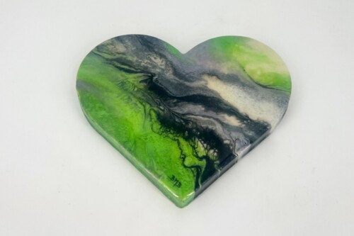 Heart-shaped resin art with green, black, and white marbling patterns on a light background.
