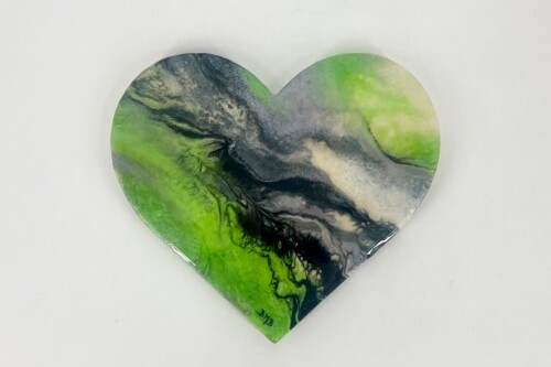 Heart-shaped decorative piece with green, black, and cream marbling on a light surface, artistically patterned.