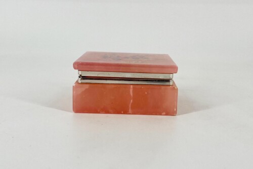 Red-orange metal stapler placed on a matching brick-red base against a plain white background.