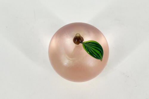 Top-down close-up of a pink fingertip with a tiny brown bud and a green striped leaf sprouting from it.