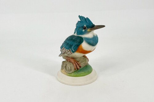 Blue kingfisher figurine perched on a small rock with a green base, white throat, orange chest, and brown beak.