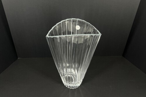 Crystal vase with vertical facets and a scalloped open top, set against a black background.