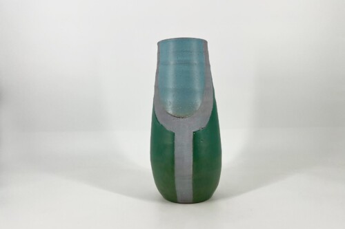 Close-up of a green bottle with a blue-tinted neck and a gray protective sleeve, showing a chipped rim at the top.