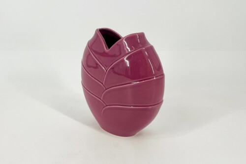 Glossy magenta ceramic vase with overlapping petal-like panels and an open top, on a white surface.
