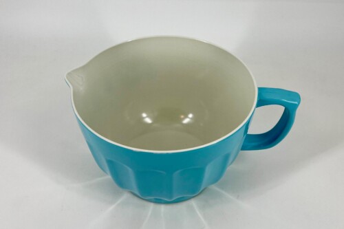 Top-down view of a bright blue ceramic mug with a small pour lip on the left, resting on a white surface.