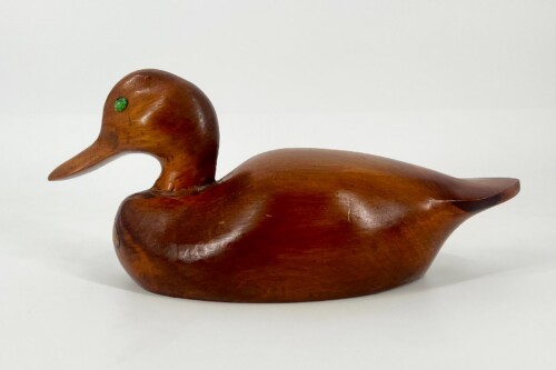 Hand-carved wooden duck sculpture with a glossy brown finish and a green bead eye on a white background.