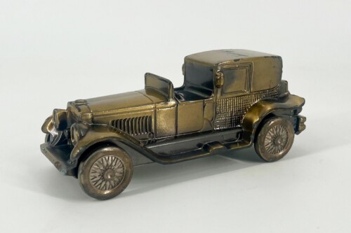 Bronze-colored metal toy car with an open driver's area and a boxy rear cabin, vintage automobile style.