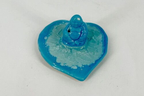 Blue heart-shaped base with a small blue clay figure perched on top, resembling a rounded creature with a small protruding nose or horn at the center.