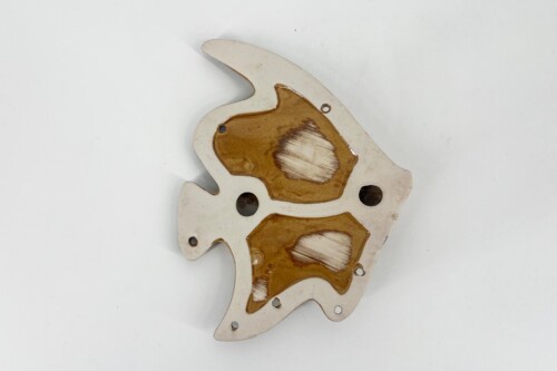 Irregular white metal plate with brown rust patches and several holes, a damaged mechanical component.