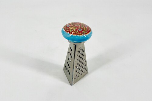 Metal hand grater with a round, colorful floral knob mounted on top