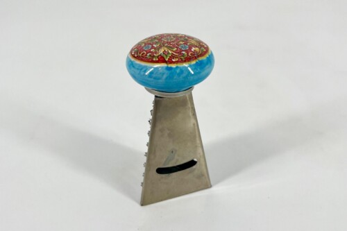 Decorative ceramic knob with a red floral pattern atop a metallic, tapered stand.