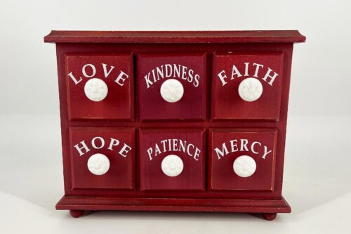 Red wooden cabinet with three drawers across top and three below, each labeled with a virtue and white knob: Love, Kindness, Faith; Hope, Patience, Mercy.