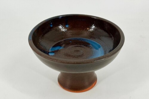 Brown wooden pedestal bowl with a glossy blue-glazed interior and orange base rim, viewed from above.