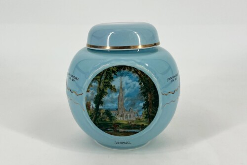 Blue lidded ceramic urn with a gold band, featuring a circular landscape scene of Salisbury Cathedral surrounded by trees and sky.