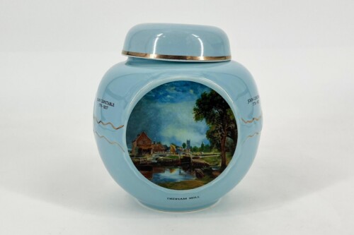 Light blue decorative jar with a gold-rimmed lid and a landscape painting of a river town on the front.