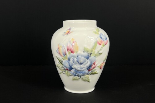White porcelain vase with a colorful floral design on a black background.