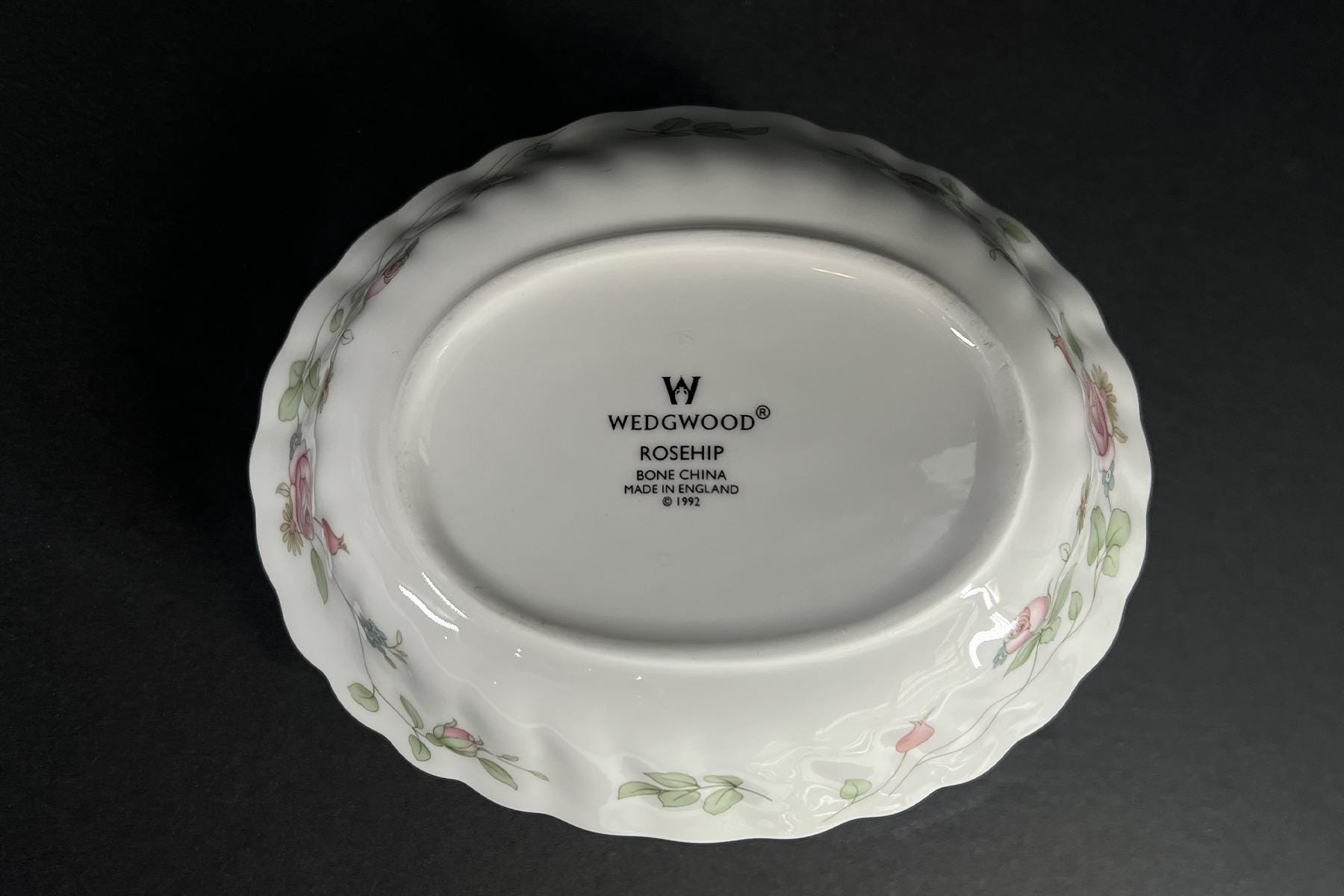 Bottom of a white decorative plate with floral border and the text 'Wedgwood Rosehip Bone China Made in England © 1992' in the center
