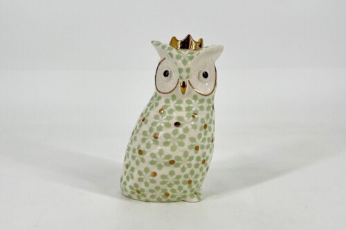 Ceramic owl figurine with a green floral pattern and a small gold crown, standing on a white surface.