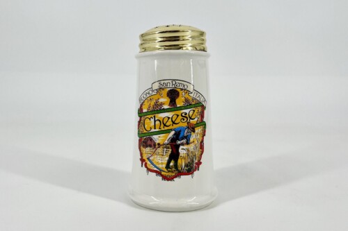 White salt shaker with a gold lid and a bright vintage label showing a farmer and the word Cheese. (informative label on a condiment container)
