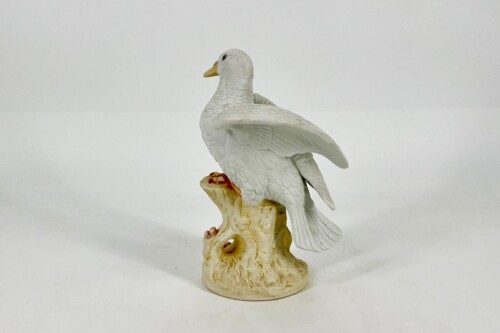 White porcelain dove sculpture perched on a textured beige base resembling a branch.