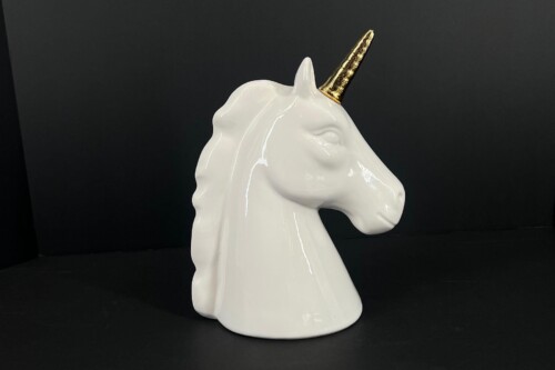 White ceramic unicorn head sculpture with a gold horn against a black background, glossy finish.