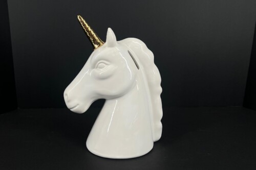 White ceramic unicorn head sculpture with a gold horn against a black backdrop (profile view).