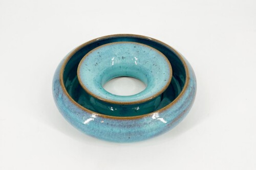 Close-up of three turquoise ceramic ring bowls nested inside each other, with brown rims visible.